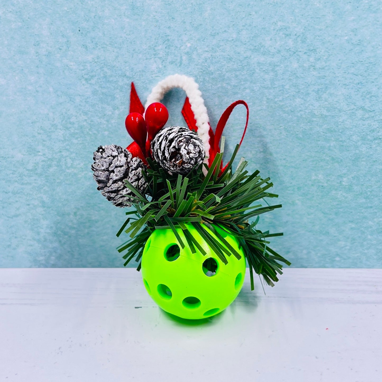 Pickleball Mistletoe  Each order gets you one mistletoe. Pickleball Christmas all year! Perfect as a gift for yourself or others. It takes up very little space for all the RV pickleballers out there. This pickleball mistletoe can be hung in the doorway or used as a Christmas tree ornament. The pickleball are adorned with plastic sprigs of holly and berries, hung with decorative ribbon and come in three sizes and many colors