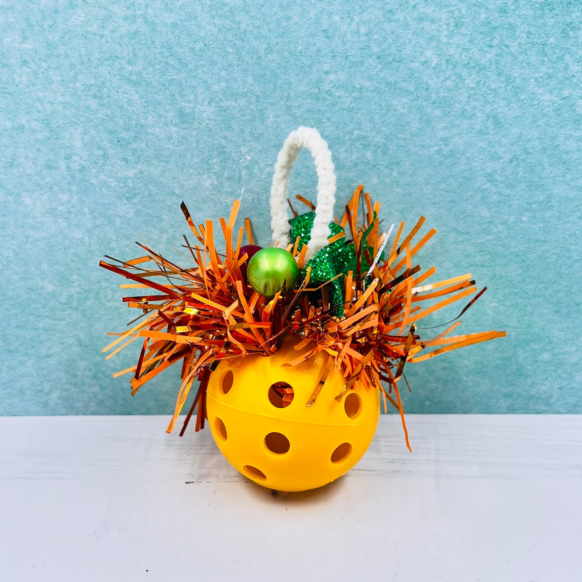 Colorful Pickleball Mistletoe.  Three sizes and customize colors.  Pickleball Christmas all year! It’s 2020, so why not? Perfect as a gift for yourself or others. It takes up very little space for all the RV pickleballers out there. This pickleball mistletoe can be hung in the doorway or used as a Christmas tree ornament. The pickleball are adorned with plastic sprigs of holly and berries, hung with decorative ribbon. 