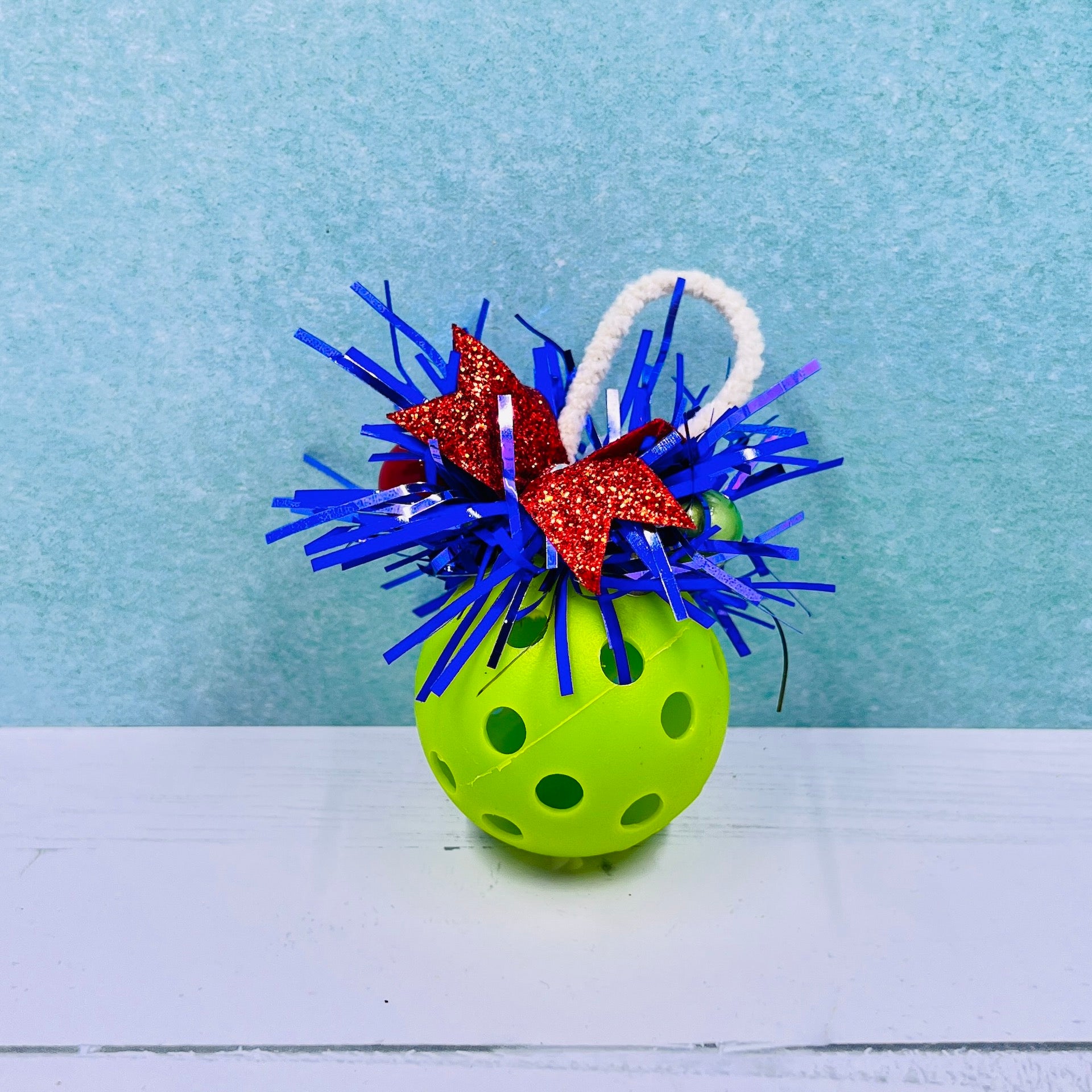 Colorful Pickleball Mistletoe.  Three sizes and customize colors.  Pickleball Christmas all year! It’s 2020, so why not? Perfect as a gift for yourself or others. It takes up very little space for all the RV pickleballers out there. This pickleball mistletoe can be hung in the doorway or used as a Christmas tree ornament. The pickleball are adorned with plastic sprigs of holly and berries, hung with decorative ribbon. 