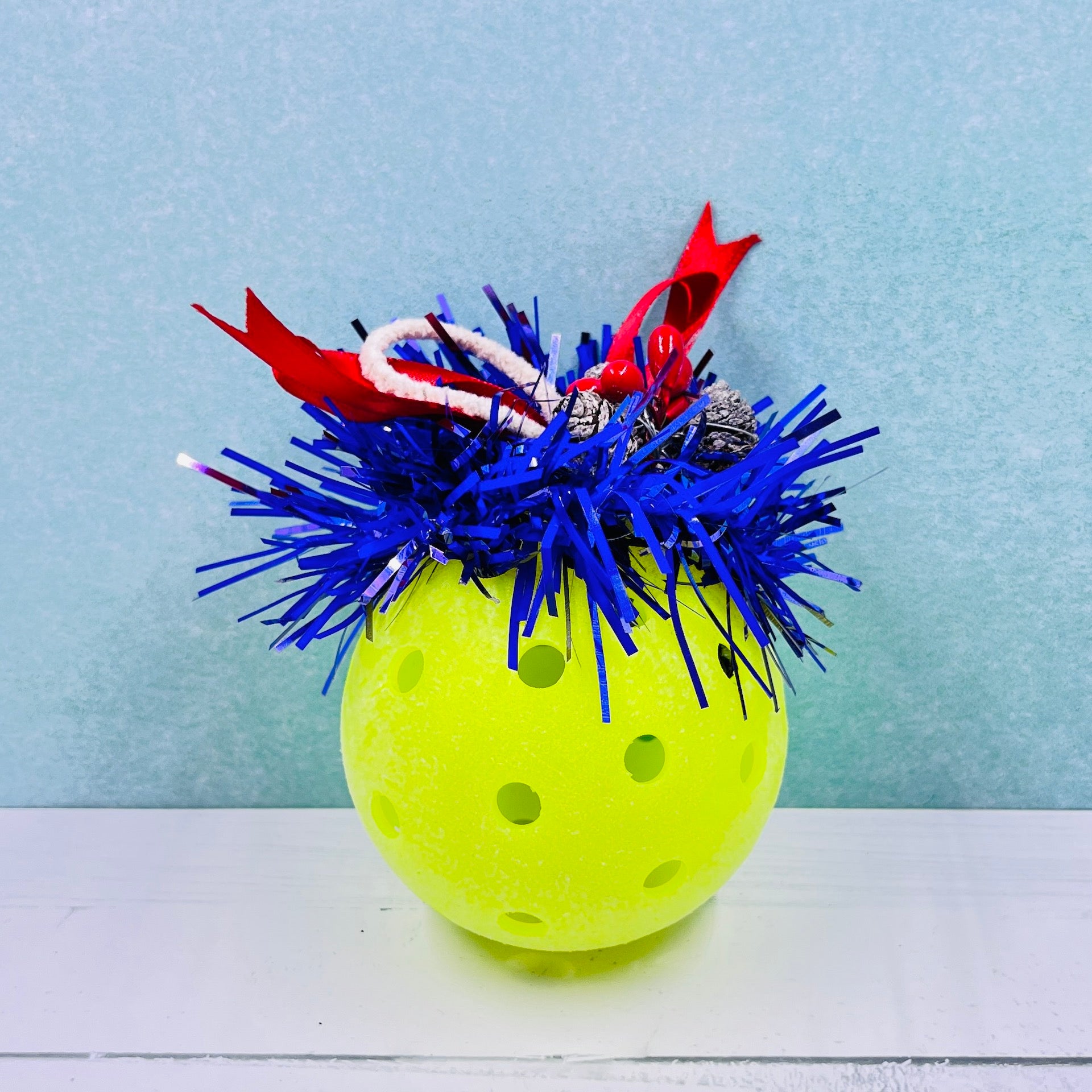 Colorful Pickleball Mistletoe.  Three sizes and customize colors.  Pickleball Christmas all year! It’s 2020, so why not? Perfect as a gift for yourself or others. It takes up very little space for all the RV pickleballers out there. This pickleball mistletoe can be hung in the doorway or used as a Christmas tree ornament. The pickleball are adorned with plastic sprigs of holly and berries, hung with decorative ribbon. 