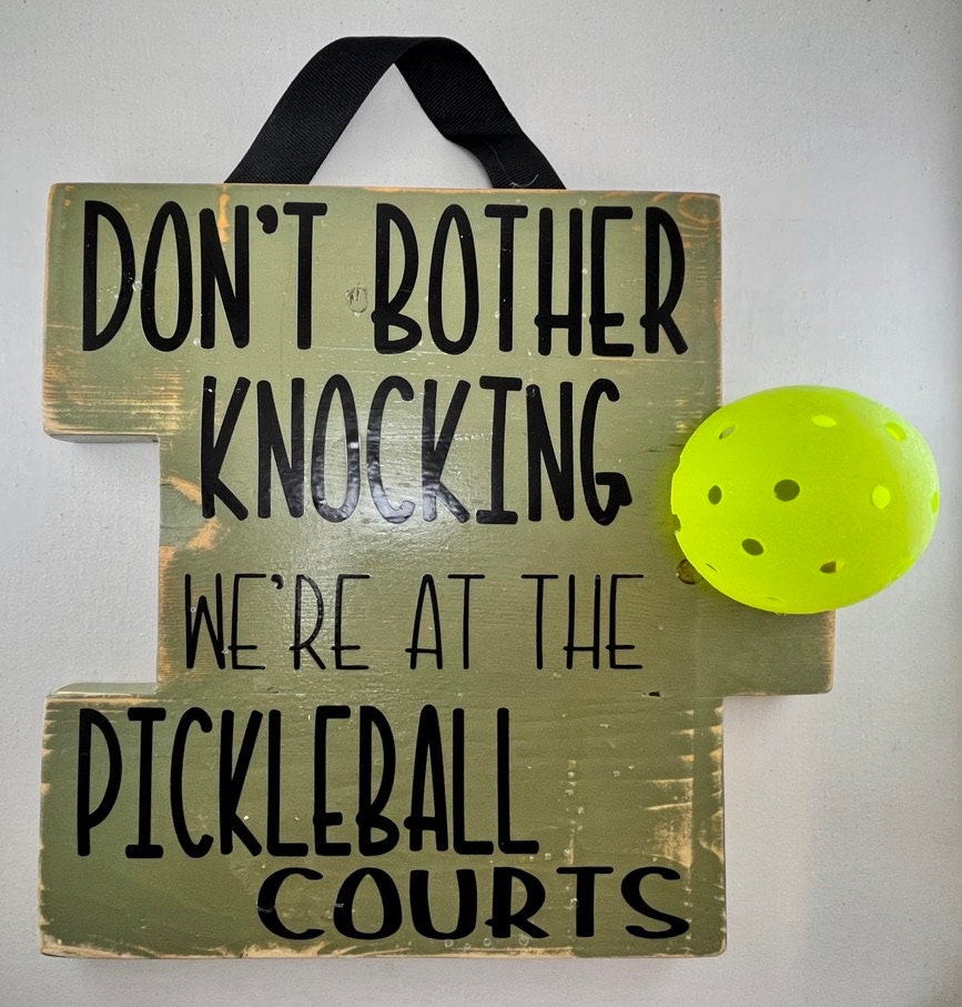 We're at the Pickleball Courts - Home Decor Door Decorations  Decorate your porch with this funny and super fun Pickleball sign. This sign uses an upcycled pickleball! It also comes in a "vintage" style. You get to customize the color of sign and the color of words you want to help match any home design.