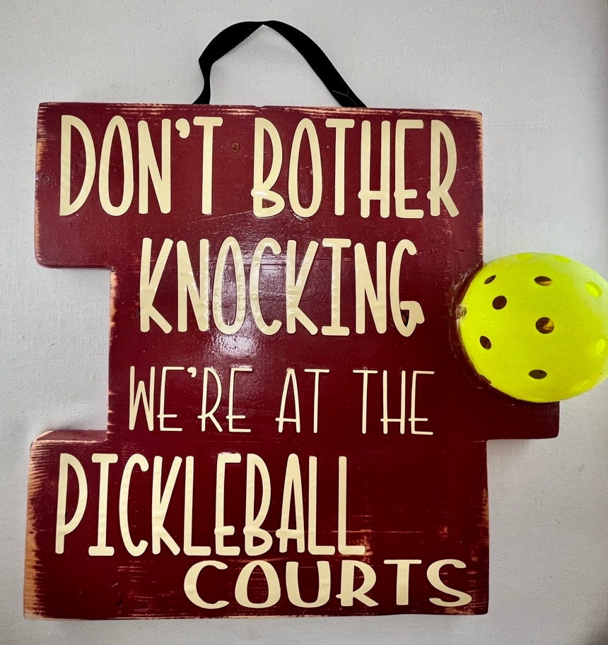 We're at the Pickleball Courts - Home Decor Door Decorations  Decorate your porch with this funny and super fun Pickleball sign. This sign uses an upcycled pickleball! It also comes in a "vintage" style. You get to customize the color of sign and the color of words you want to help match any home design.