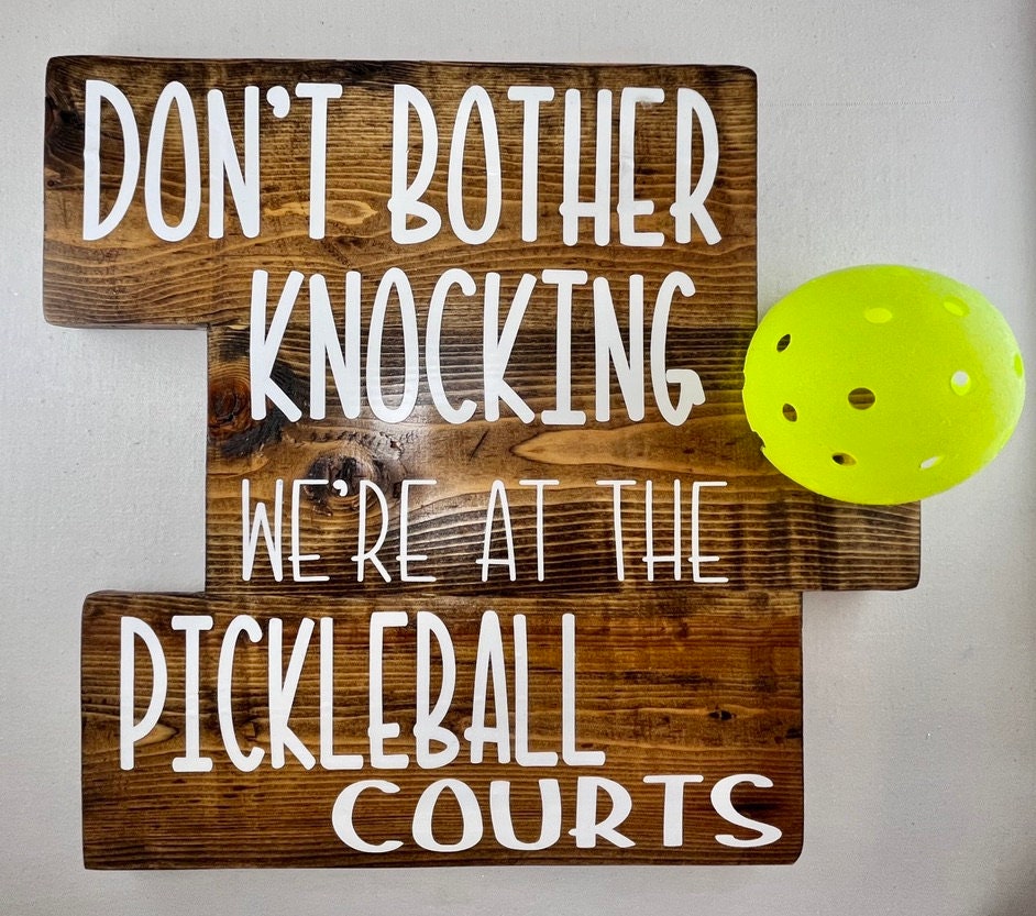 We're at the Pickleball Courts - Home Decor Door Decorations  Decorate your porch with this funny and super fun Pickleball sign. This sign uses an upcycled pickleball! It also comes in a "vintage" style. You get to customize the color of sign and the color of words you want to help match any home design.
