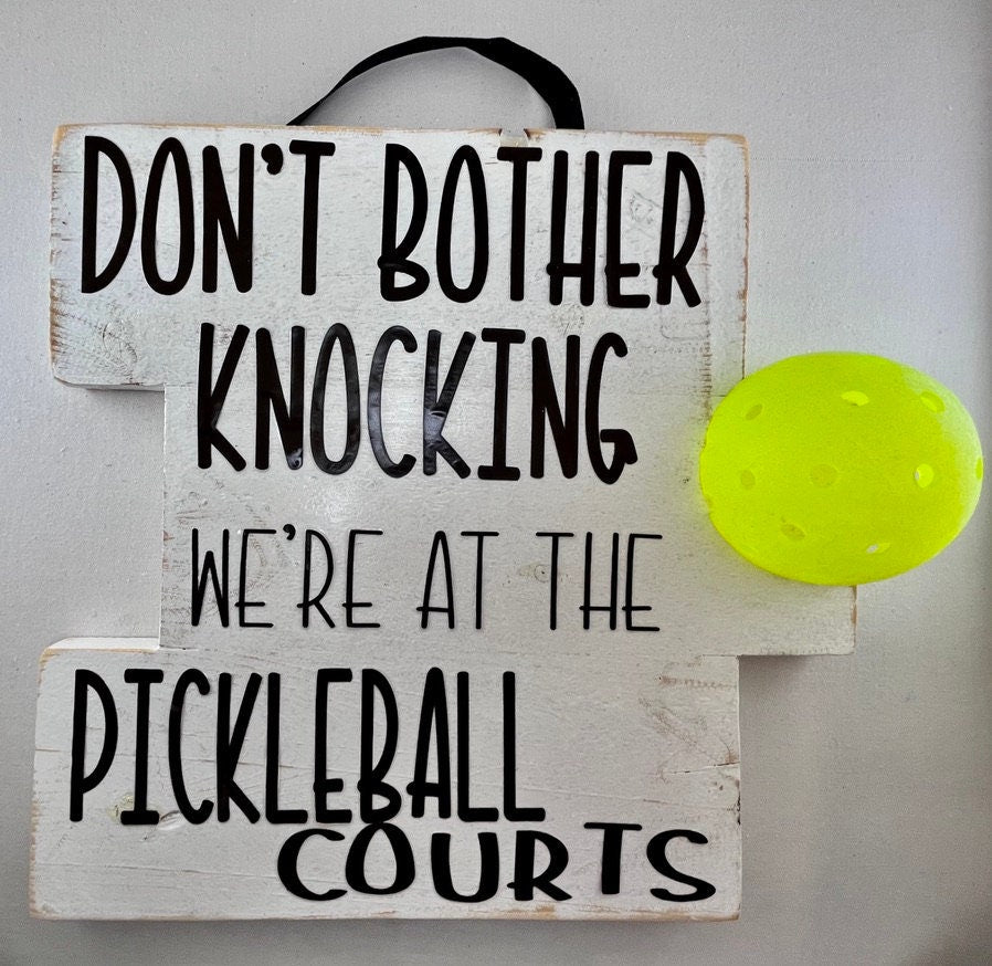 We're at the Pickleball Courts - Home Decor Door Decorations  Decorate your porch with this funny and super fun Pickleball sign. This sign uses an upcycled pickleball! It also comes in a "vintage" style. You get to customize the color of sign and the color of words you want to help match any home design.